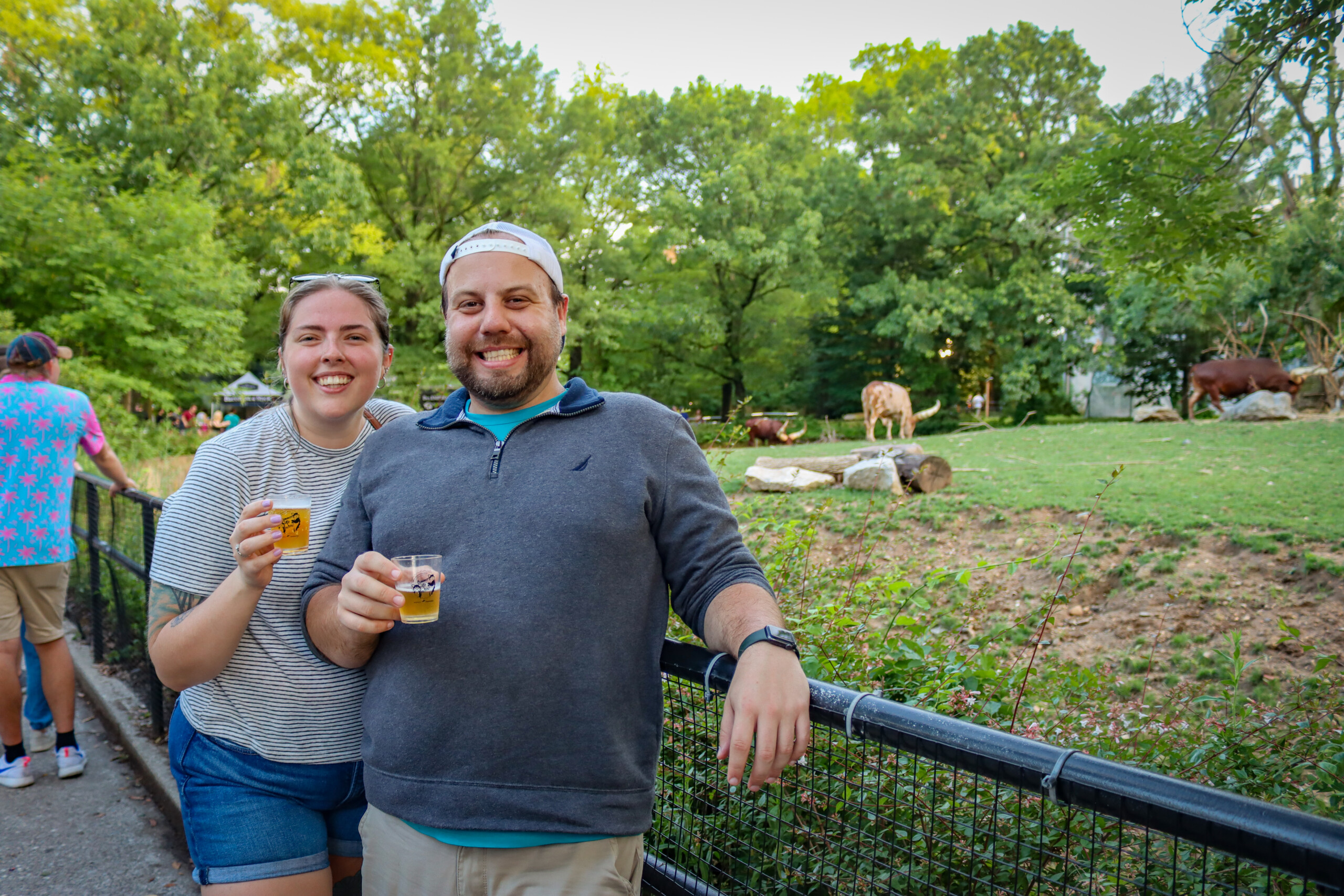 A couple poses for a photo next to the Ankole cattle habitat in African Plains during Summer Ale Festival, Philly Zoo's annual beer fest.